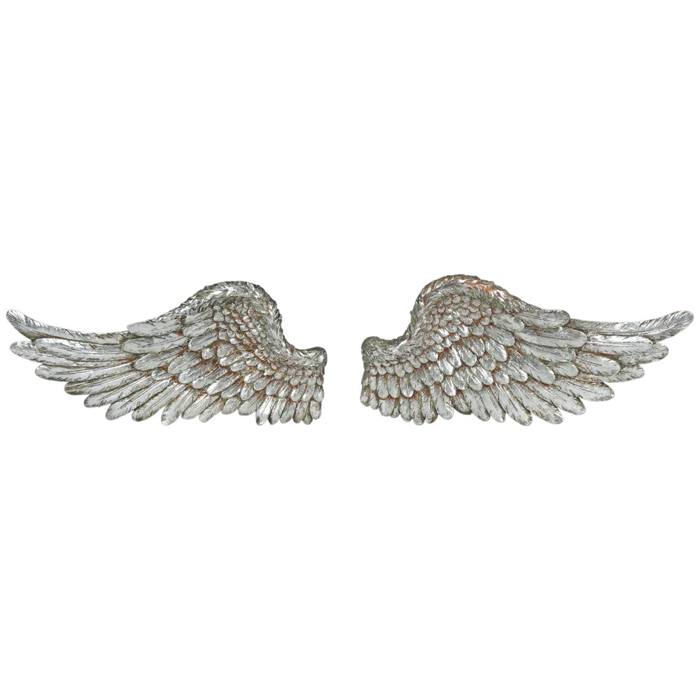 A pair of distressed silver angel wings wall decor mounted on a dark olive green wall above a wooden console table with a ceramic vase and books.