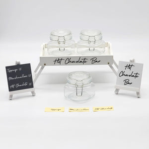 Hot chocolate bar setup with jars and signs on a white background