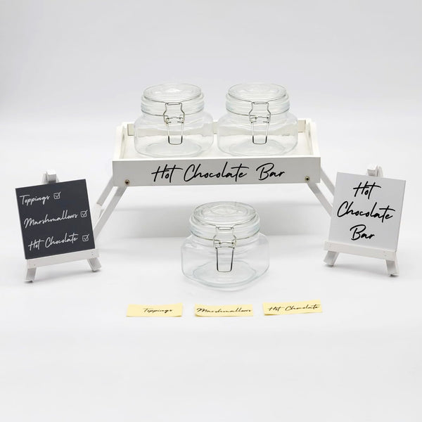 Hot chocolate bar setup with jars and signs on a white background