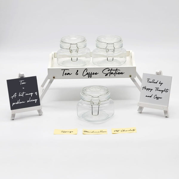 Tea and coffee station setup with glass jars and decorative signs on a white background