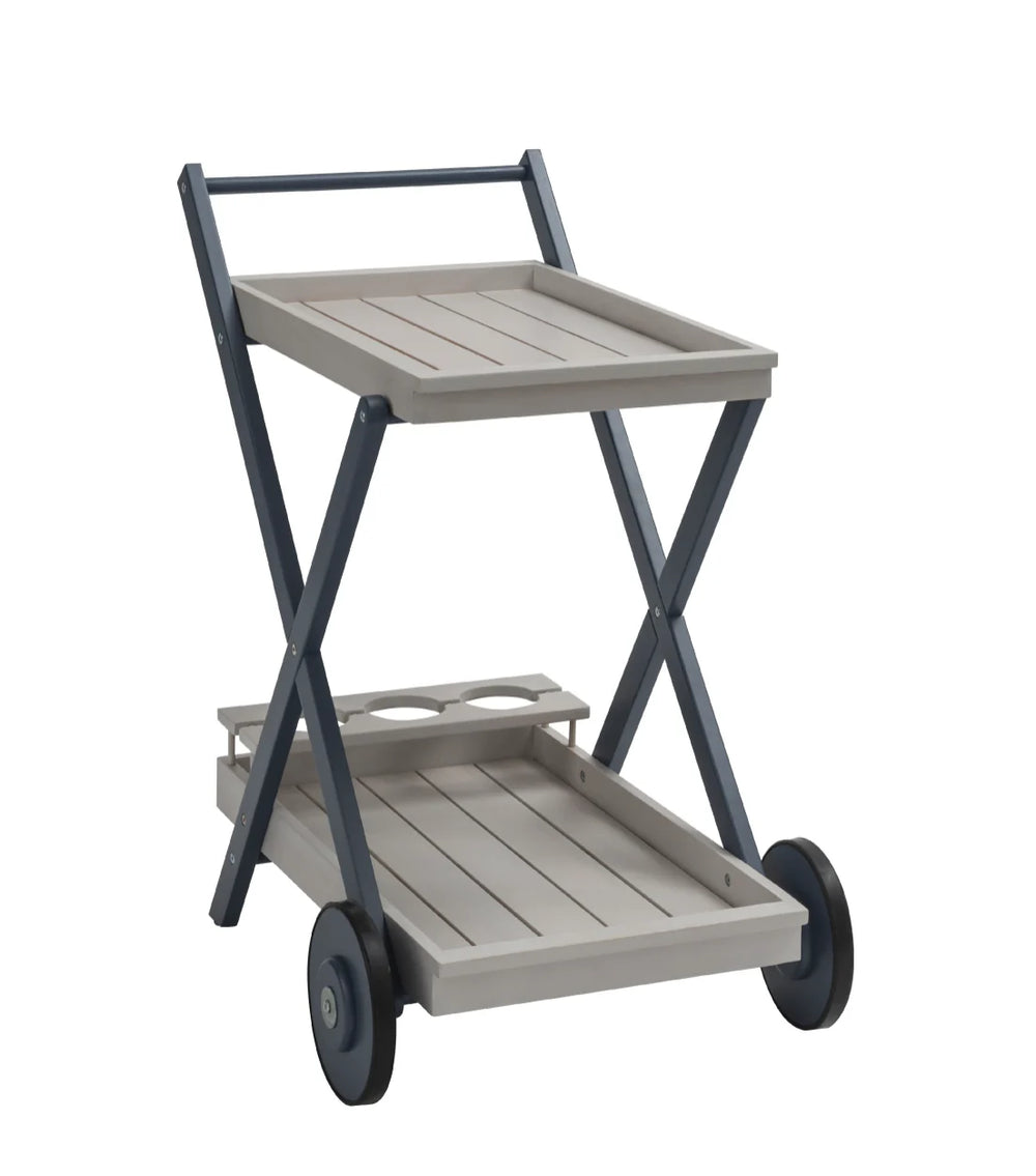 A stylish greywash drinks trolley with glass holders and wheels, set on a patio with outdoor furniture in the background.