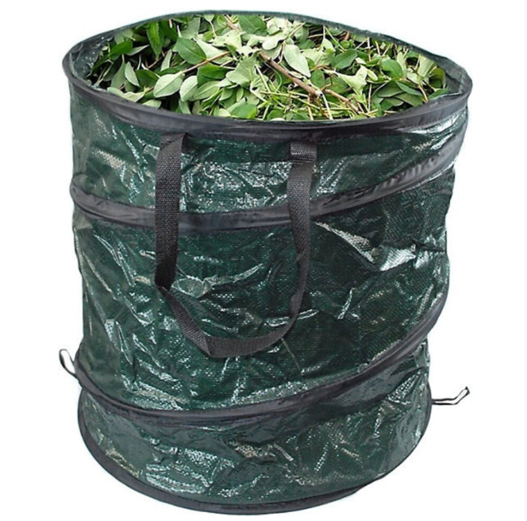 Green garden waste bag filled with leaves on a stone surface outdoors.
