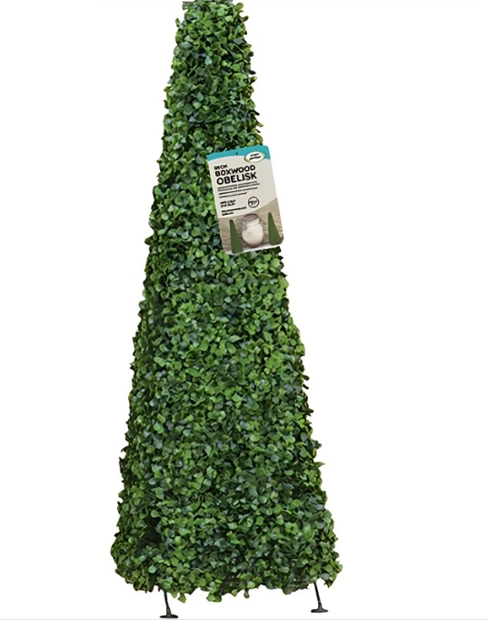 Tall green artificial topiary against a stone wall