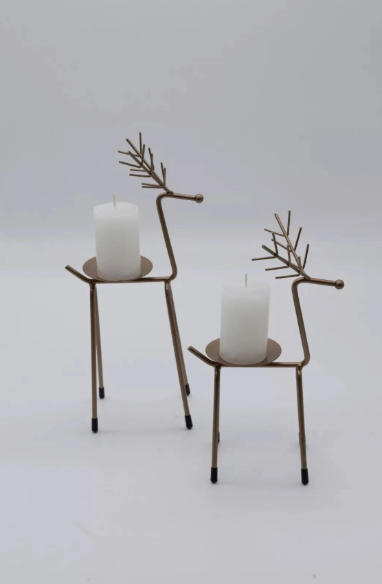 Two decorative reindeer candle holders with lit candles on a wooden surface.