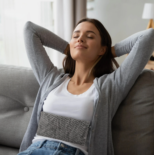 Woman relaxing on a couch with her arms behind her head in a cozy living room.