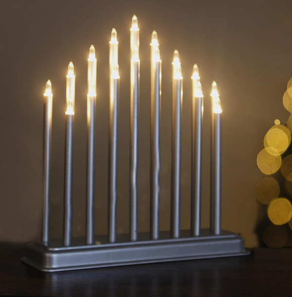 Metallic Menorah with lit candles against a dark background