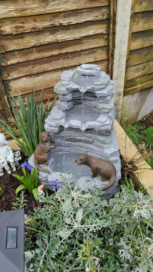 Decorative stone fountain with animal sculptures in a garden setting.