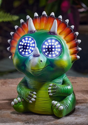 Green dinosaur figurine with blue glowing eyes on a wooden surface