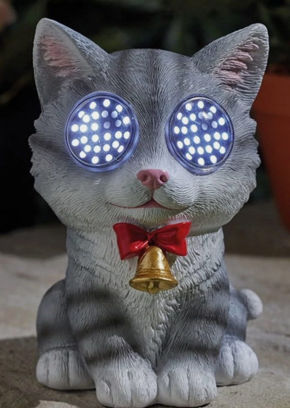 Solar resin cat with eyes lit up, sitting in a garden
