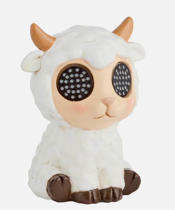 Small figurine of a lamb with glowing blue eyes on a wooden surface.