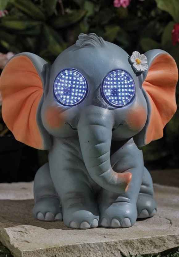 Decorative elephant figurine with glowing eyes on a stone surface.
