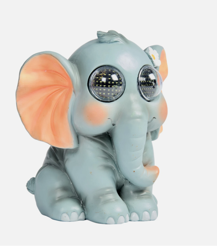 Decorative elephant figurine with glowing eyes on a stone surface.