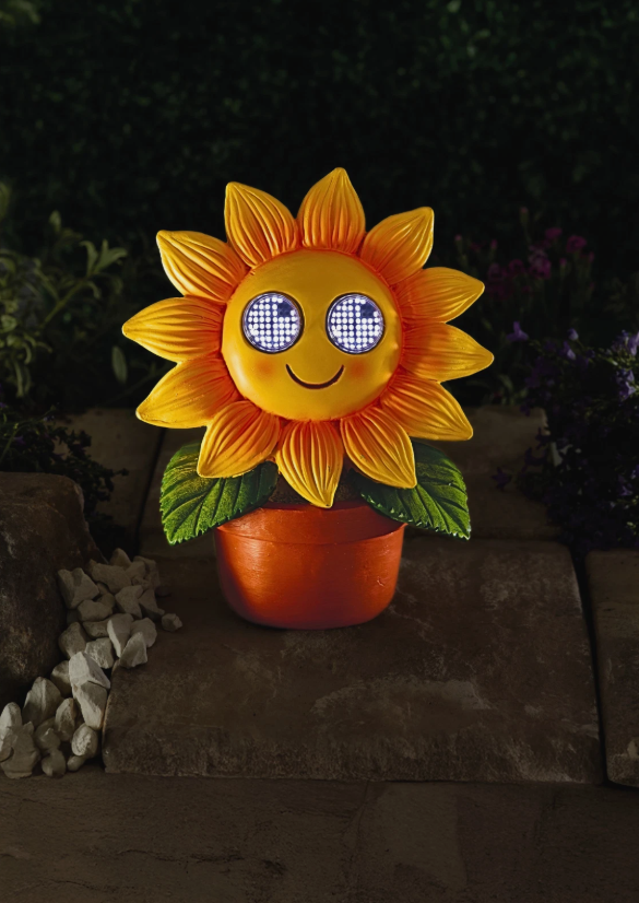 Sunflower-shaped decorative light with a smiling face on a dark background