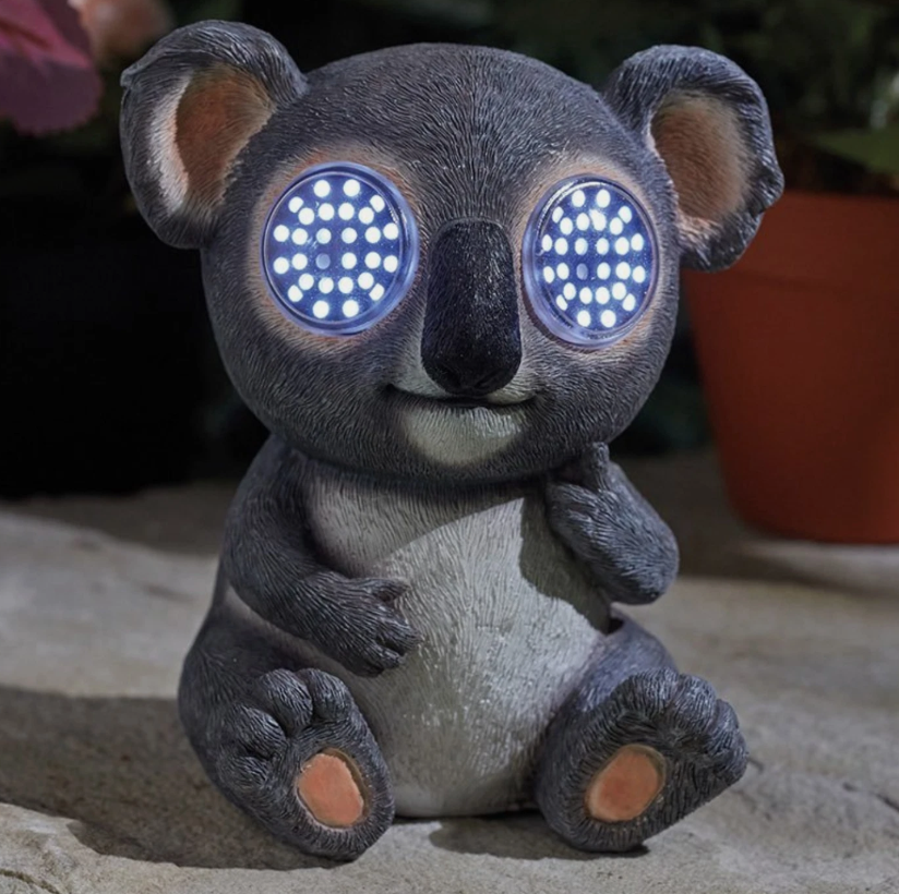 Decorative koala figurine with glowing eyes on a stone surface.