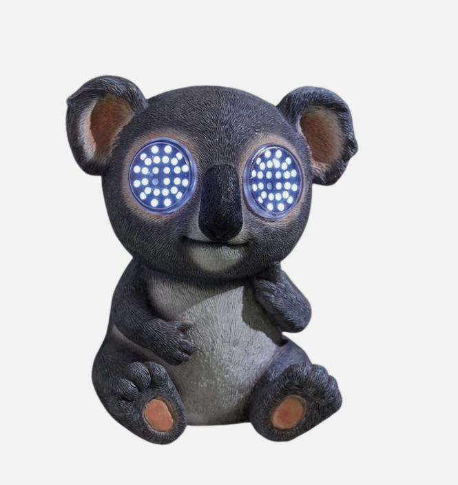 Decorative koala figurine with glowing eyes on a stone surface.