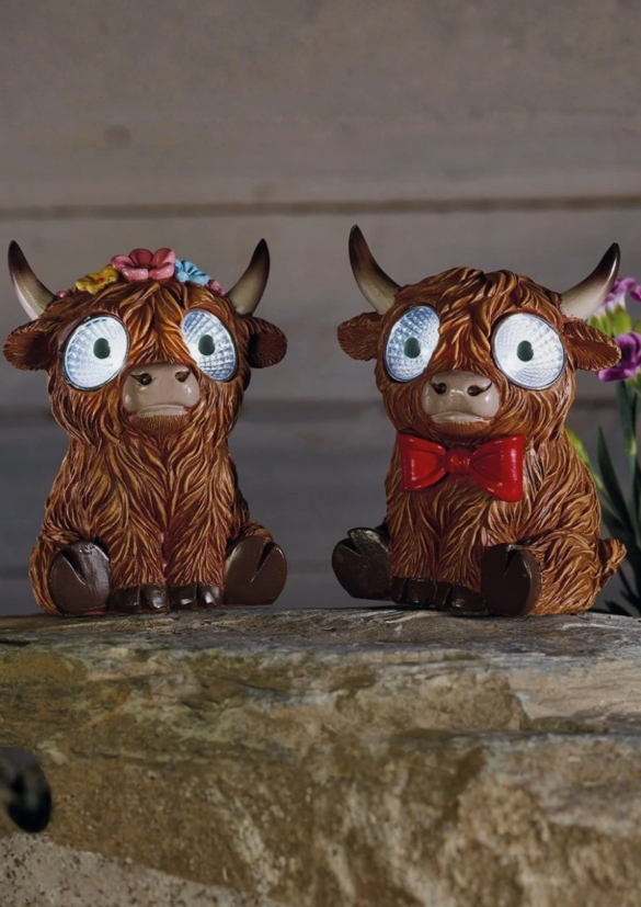 Two decorative figurines of brown animals with large eyes on a stone surface.