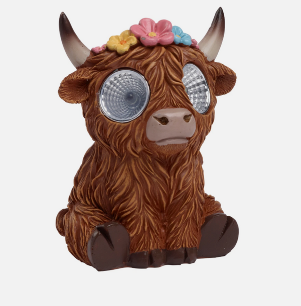 Toy figure of a highland cow with floral headband on a white background