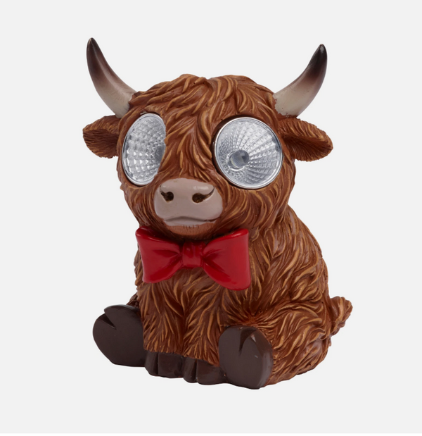 Brown figurine of a bull with googly eyes and a red bow tie on a white background