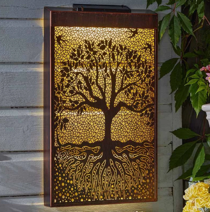 Decorative outdoor light with tree design on a wooden surface
