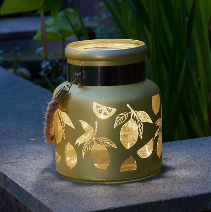 Decorative lantern with lemon designs on a stone surface outdoors
