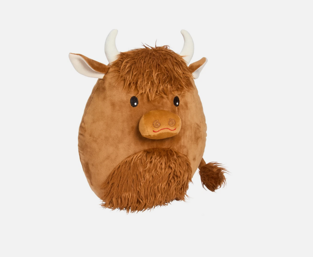 Plush toy Highland cow on a gray couch with a neutral background