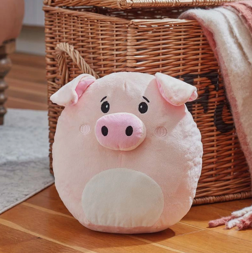 Plush pig toy on a wooden floor with a wicker basket in the background