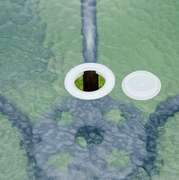 Close-up of a drain with two white covers on a green and gray textured background