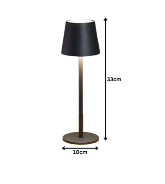 A black USB rechargeable table lamp placed on a wooden round table, with a yellow bottle and white flowers on the side.
