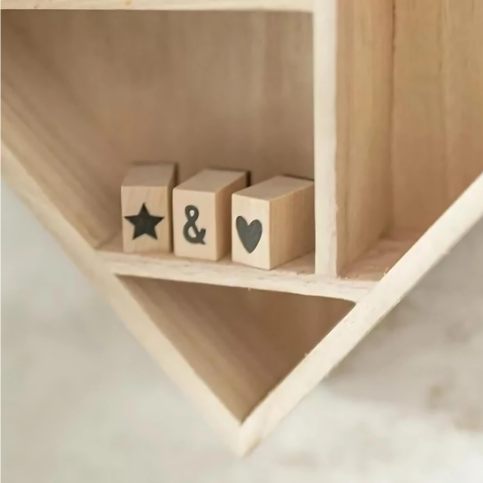 Three wooden blocks with star, ampersand, and heart symbols on a wooden shelf.