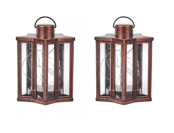 Two bronze effect star-shaped solar garden lanterns with firefly lighting effect, placed on a wooden surface outdoors.