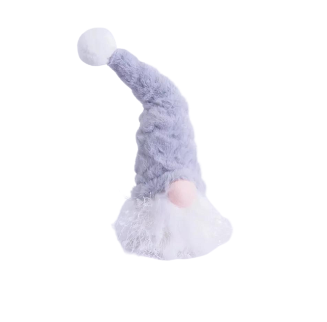 A plush grey gonk Christmas ornament with an LED light creating a warm glow, displayed on a table with pine cones and a blurred Christmas tree in the background.