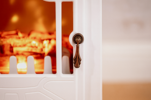Close-up of a white cabinet with a gold handle, blurred background
