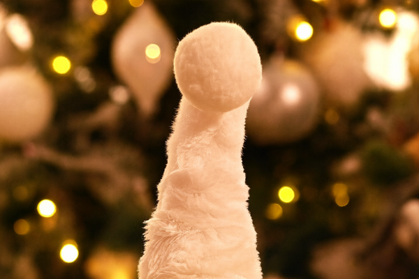 Close-up of a plush toy with a blurred Christmas tree in the background