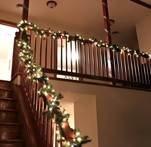Decorative Christmas garland with lights on a staircase railing.