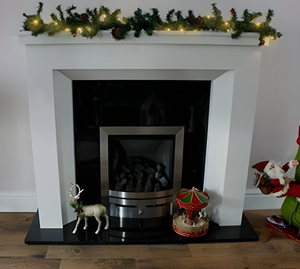 White fireplace with decorative items and a Christmas garland.