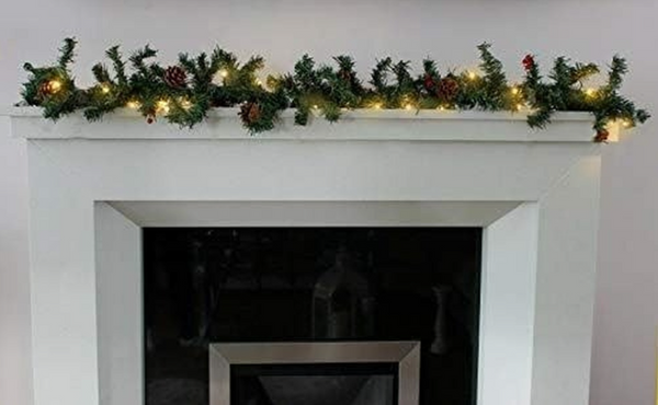 Decorative Christmas garland with lights on a white fireplace mantel.