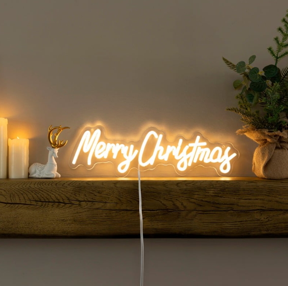 Neon 'Merry Christmas' sign with a Christmas tree and gift box on a warm-toned background