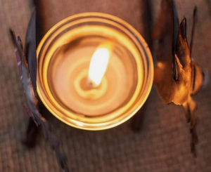 Candle in a decorative holder with a warm glow on a textured surface