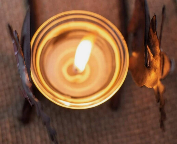 Candle in a decorative holder with a warm glow on a textured surface
