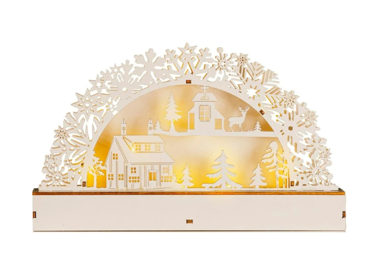 A white wooden pre-lit village scene with intricate snowflakes, illuminated by LED lights, displayed against a dark background.