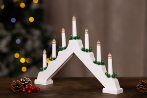 Decorative white arch with candles in front of a blurred Christmas tree with lights.