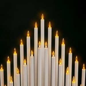 Multiple white candles with lit wicks against a black background