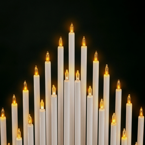 Multiple white candles with lit wicks against a black background