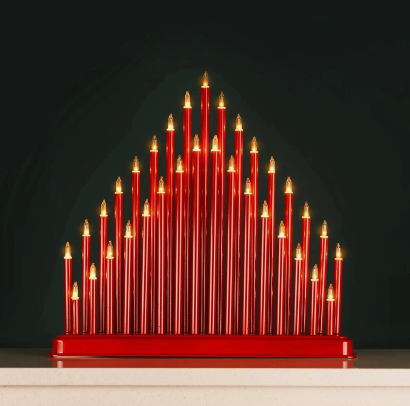 Red candle-like sculpture with gold accents on a dark background