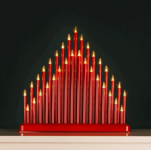 Red candle-like sculpture with gold accents on a dark background