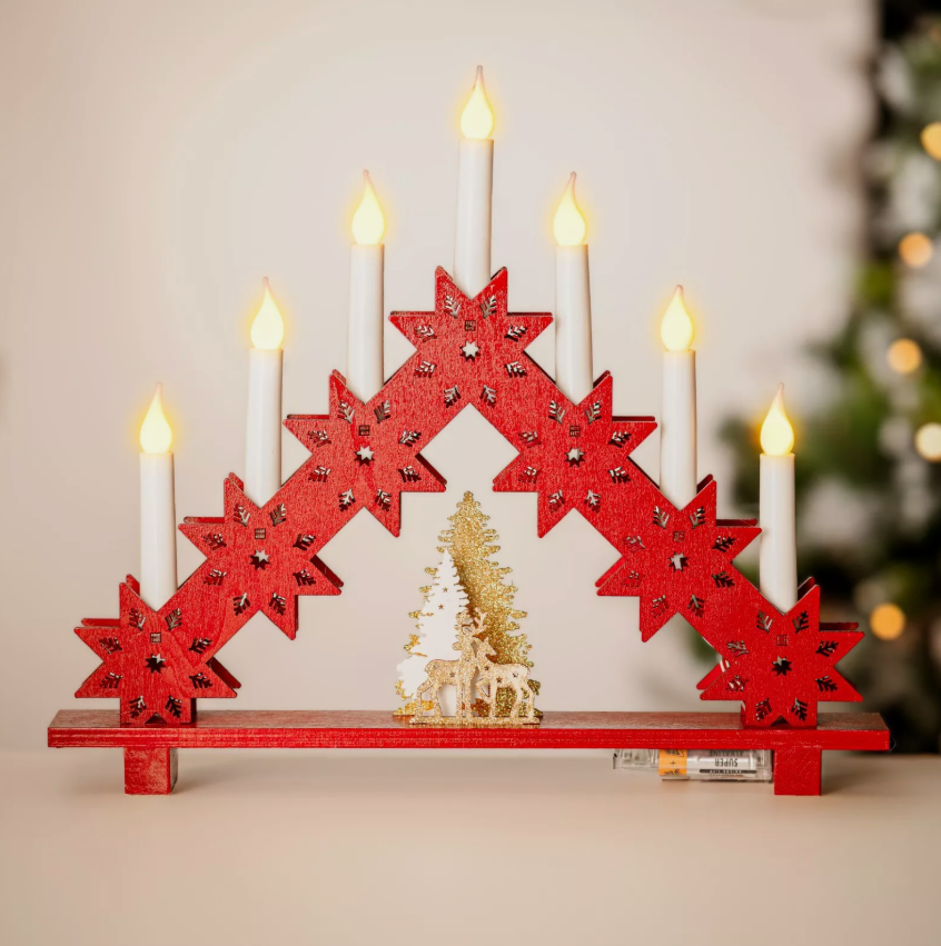 Decorative Advent wreath with red stars and lit candles on a neutral background