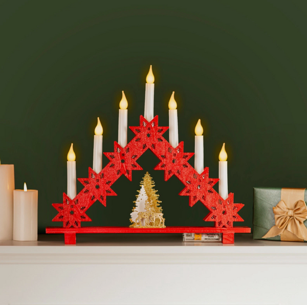 Red star-shaped candle holder with lit candles on a green background