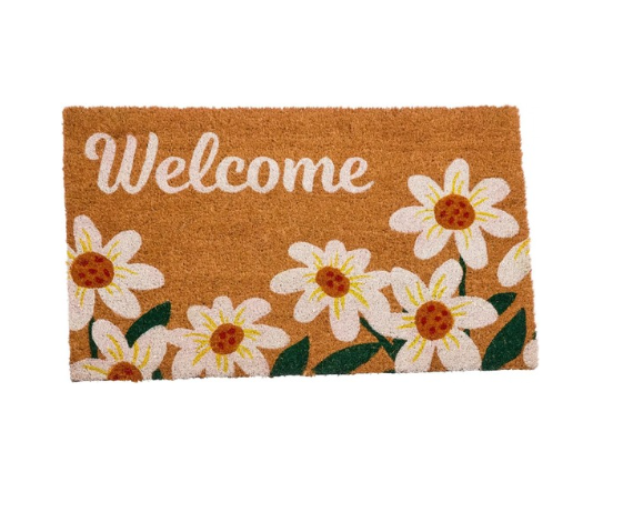 Doormat with daisy design and 'Welcome' text on a stone pathway.