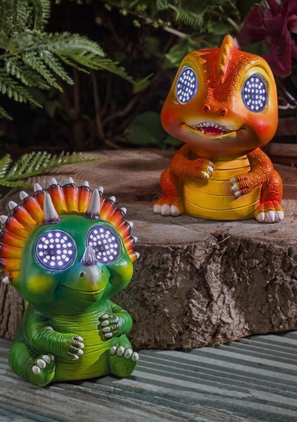 Two colorful dinosaur figurines with glowing eyes on a wooden surface.