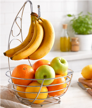 Fruit basket with bananas, apples, and oranges on a kitchen counter.